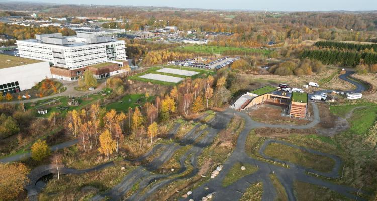 Dronefoto af trailcentret med Skanderborg Fælled, legeplads, beachvolley og parkeringsplads i baggrunden.